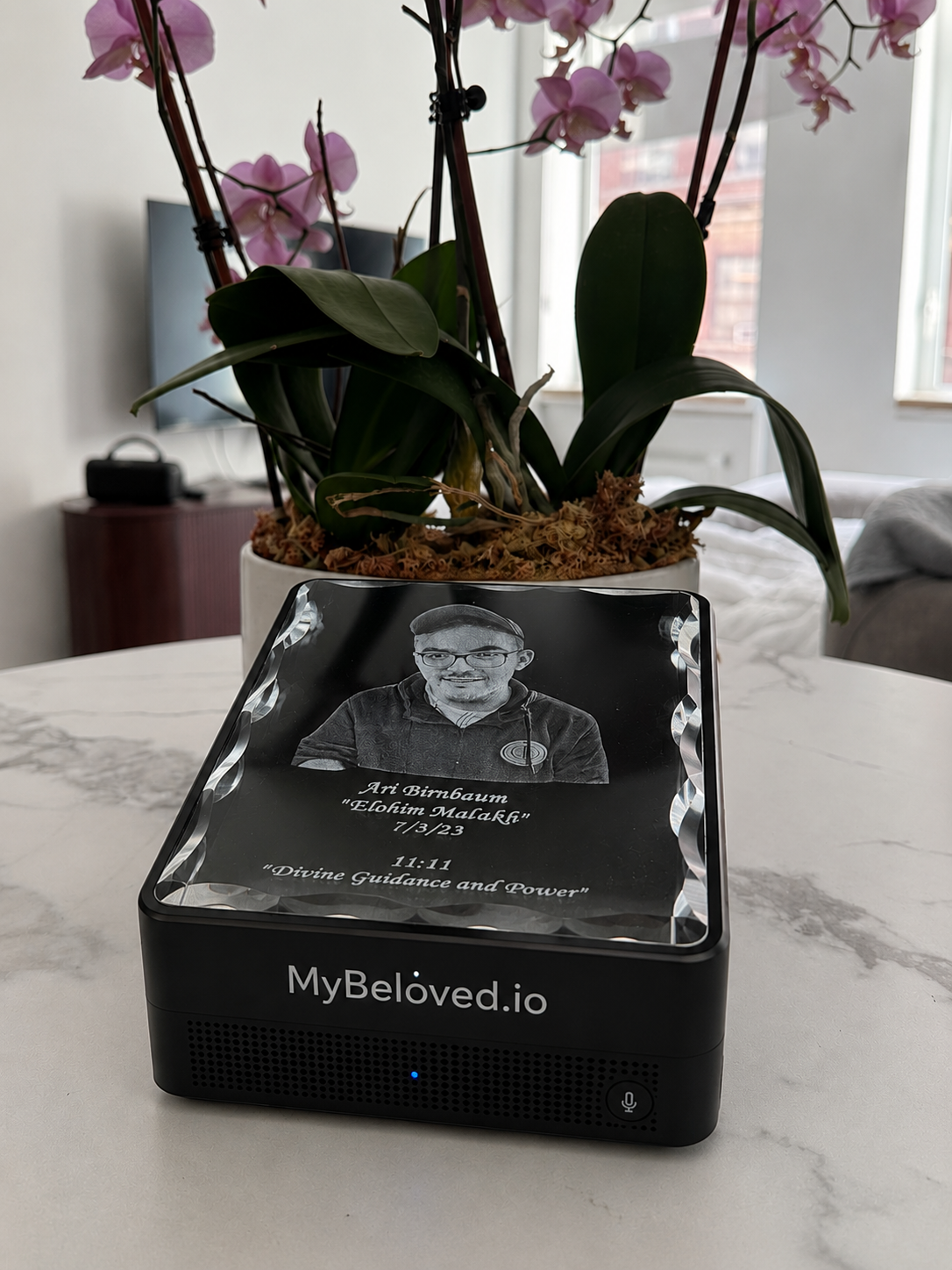 My Beloved memorial device: a laser-engraved crystal portrait on a matte black base with a microphone button and a soft blue status light.